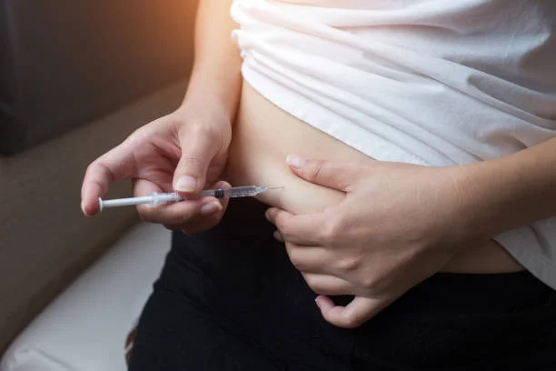 Woman with syringe inject insulin to her belly diabetes concept
