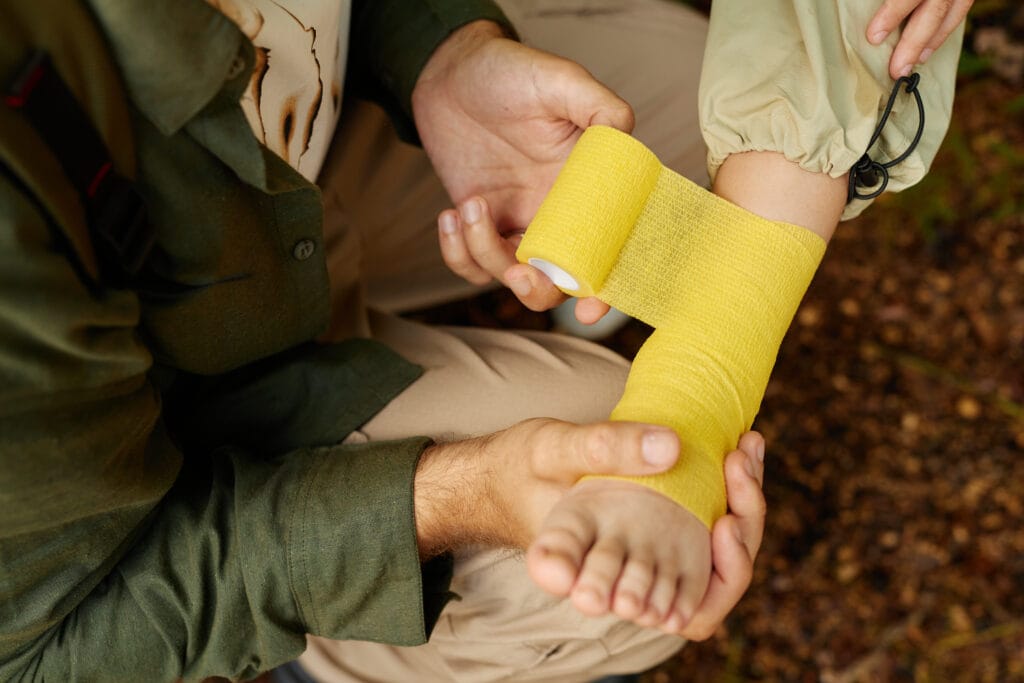 Wrapping Yellow Bandage Around Child's Injured Arm